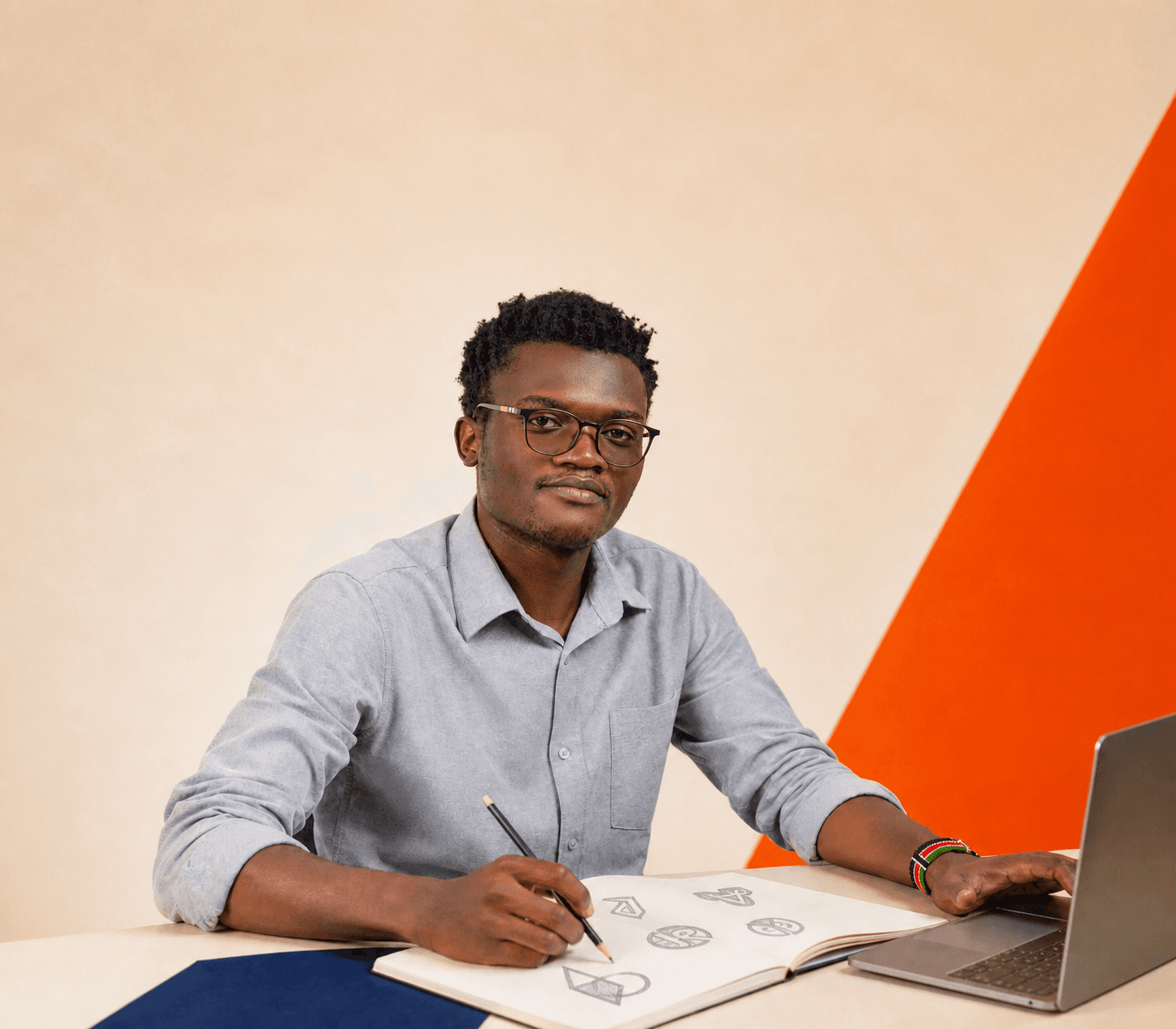 Creative portrait of Don Omondi sketching logo concepts beside a laptop