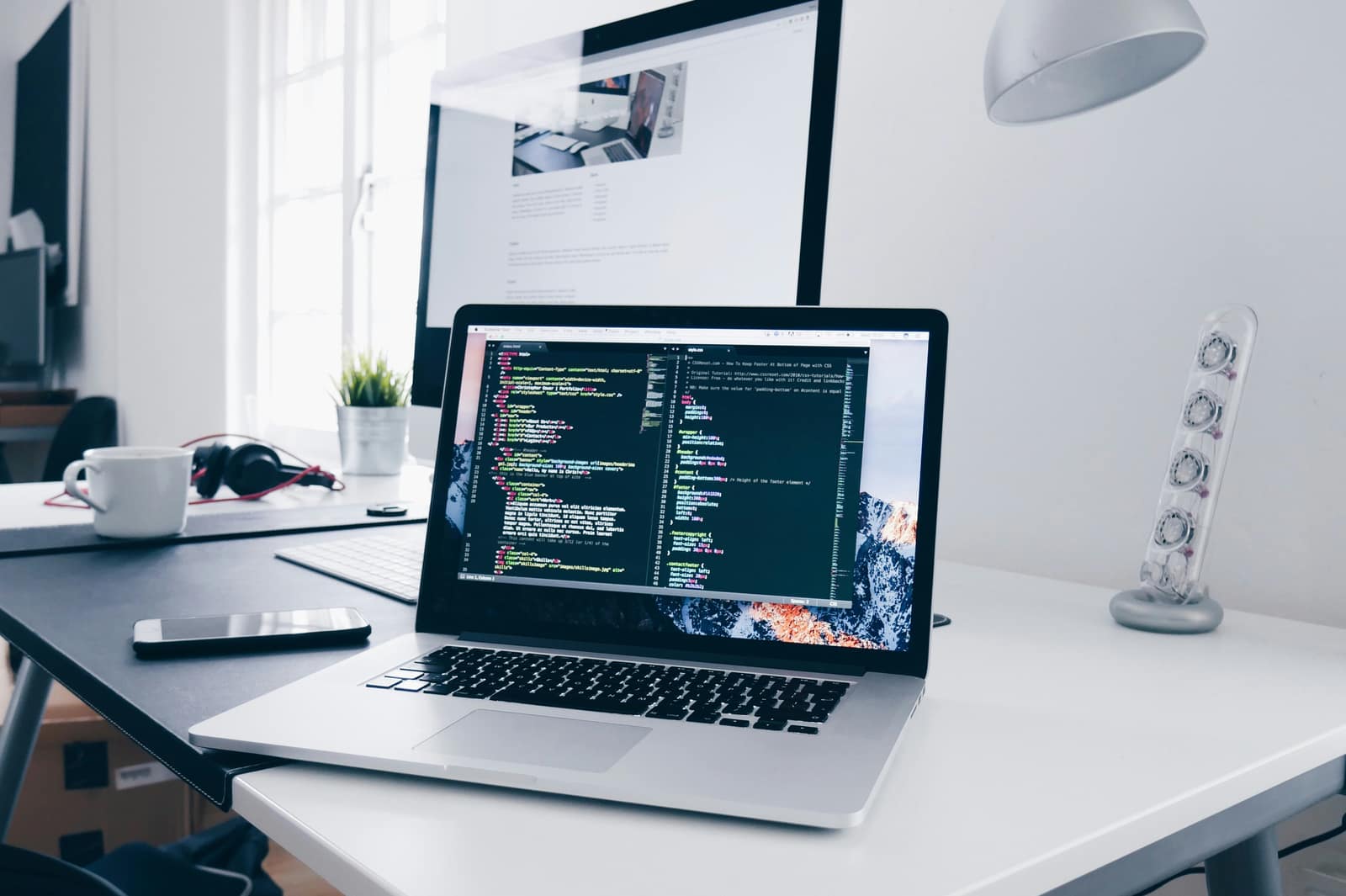 A developer workspace in Nairobi with a mobile app build open on a laptop and a second screen
